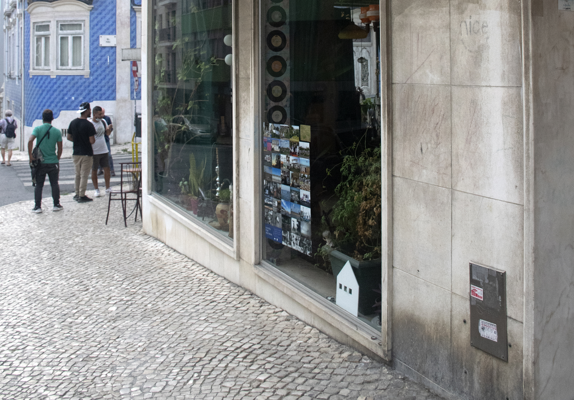 A street in Lisbon, Portugal. In one of the shop windows there is an exhibition of Shutter Hubs Postcards from Great Britain project, lots of postcard sized photographs