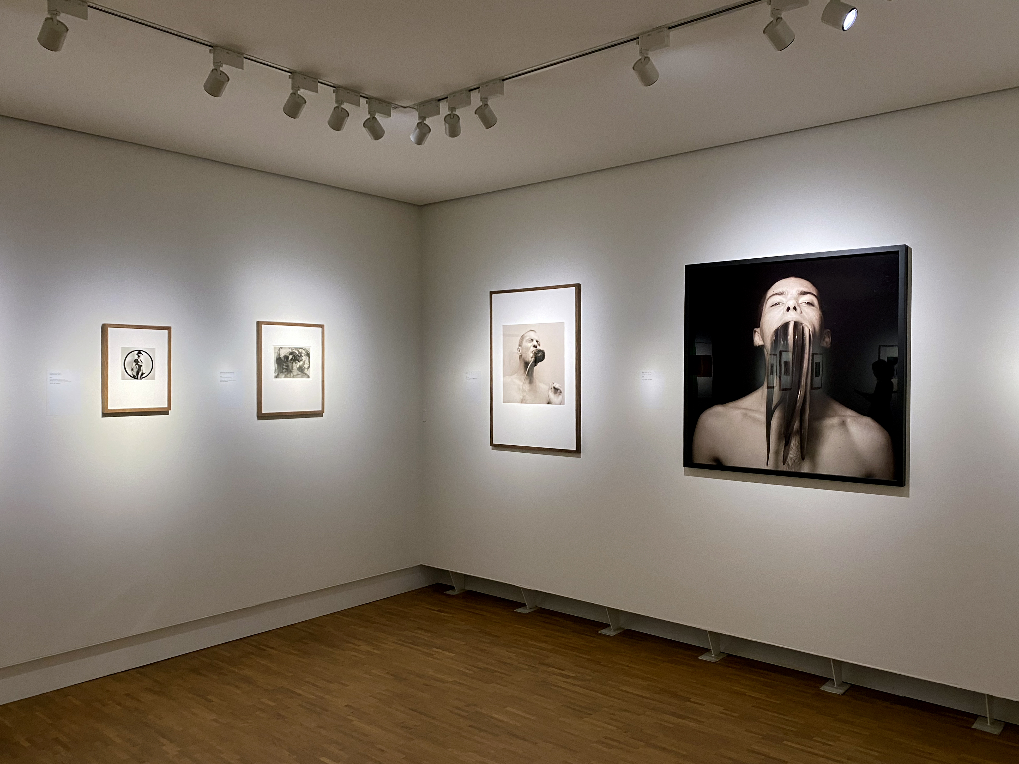 Installation photograph of Paul Blanca at fotomuseum Den Haag, showing the corner of white-walled gallery with framed photographs and lighting visible on a track above.