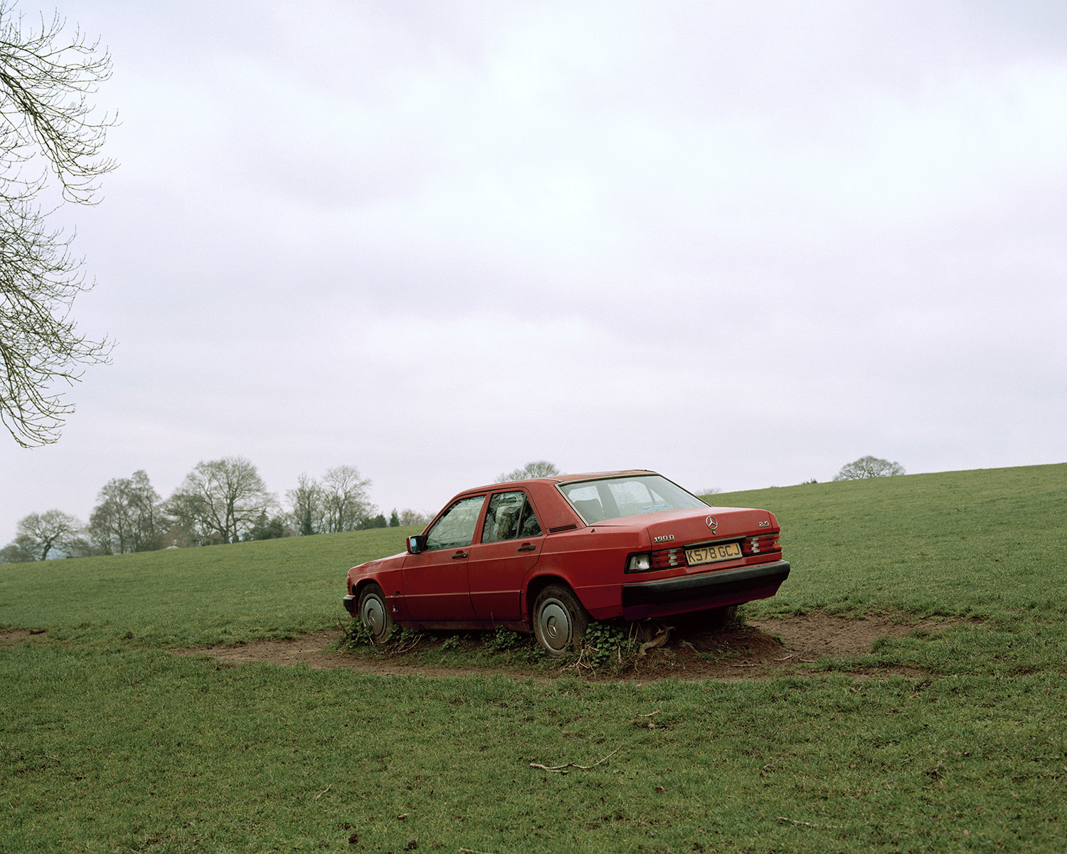 Photograph of an old red Mercedes in a field