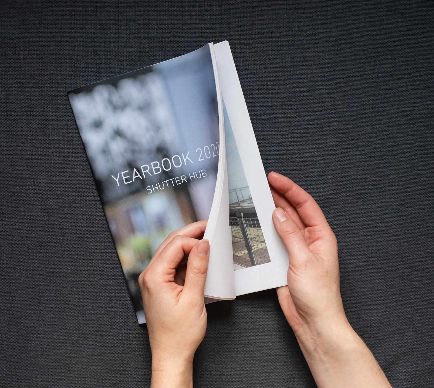 Hands flicking through the YEARBOOK 2020 printed publication, against a grey background.