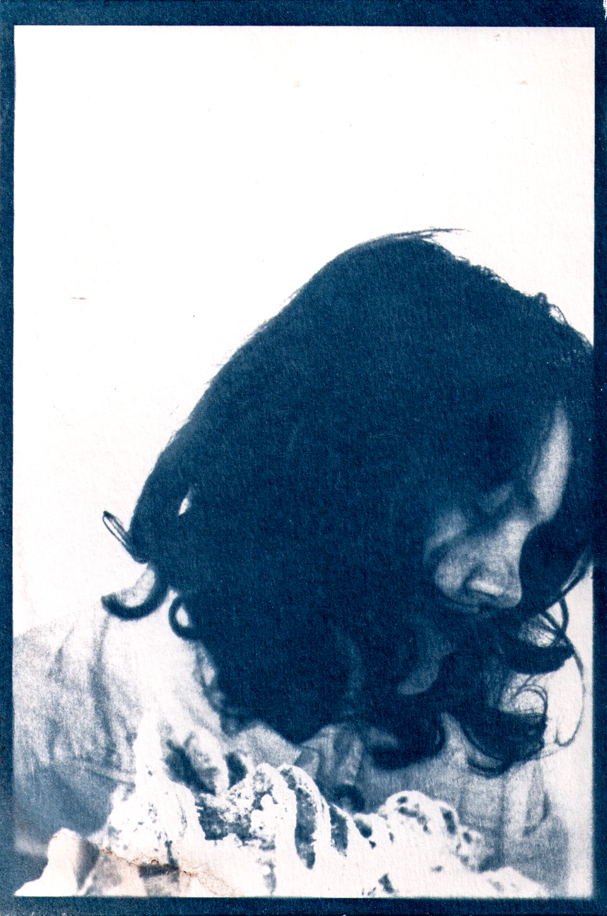Photo of a female looking down and away from the camera, in front of her is a shell.